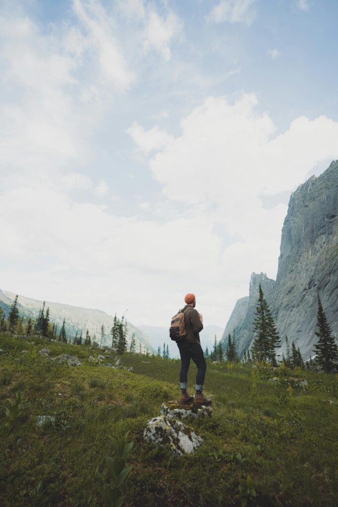 A lone hiker stands in a vast mountainous landscape, embracing nature's grandeur.
